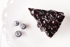   Cheesecake with a layer of tasty biscuits, covered with blueberry jam